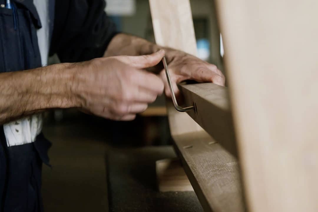 Un artisan monte une table en bois massif